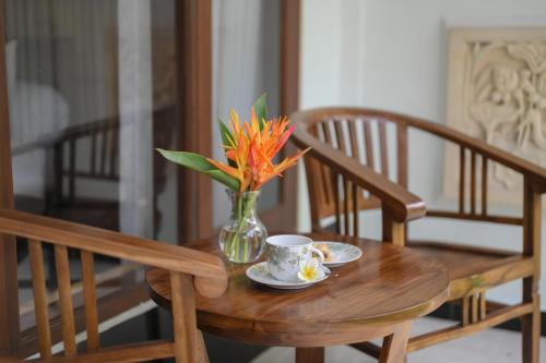 een tafel met een vaas met bloemen en een kopje koffie bij Tiga Naga Villa in Denpasar