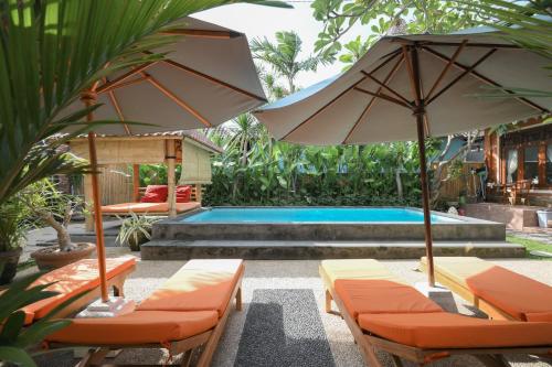 a pool with chairs and umbrellas in front of a pool at Tiga Naga Villa in Denpasar