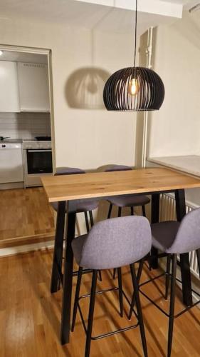 a dining room table with chairs and a pendant light at Mysigt Stadsoas: En Modern lägenhet med 2 sovrum in Gothenburg