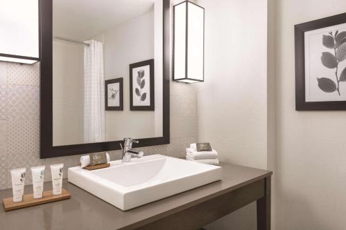 ein Badezimmer mit einem weißen Waschbecken und einem Spiegel in der Unterkunft Country Inn & Suites by Radisson, Williamsburg East Busch Gardens , VA in Williamsburg