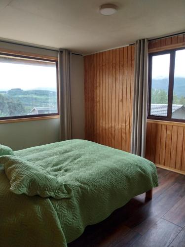 ein Schlafzimmer mit einem grünen Bett und einem Fenster in der Unterkunft Casa Cerro Divisadero in Coihaique