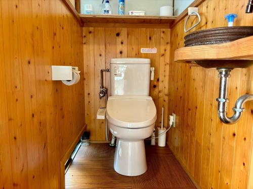 a bathroom with a toilet in a wooden wall at 城跡石垣上の絶景古民家宿 鞆城茶屋庵 in Tomo