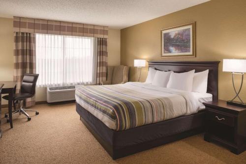 a hotel room with a bed and a desk and a window at Country Inn & Suites by Radisson, West Bend, WI in West Bend
