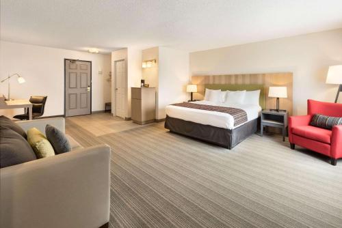 Country Inn & Suites by Radisson, Chippewa Falls, WI في شبوا فولز: غرفة بالفندق سرير وكرسي احمر