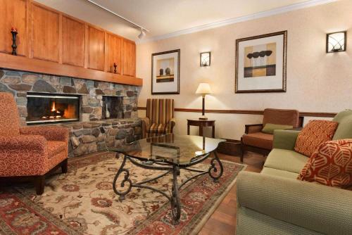 a living room with a fireplace and a couch and chairs at Country Inn & Suites by Radisson, Stevens Point, WI in Stevens Point