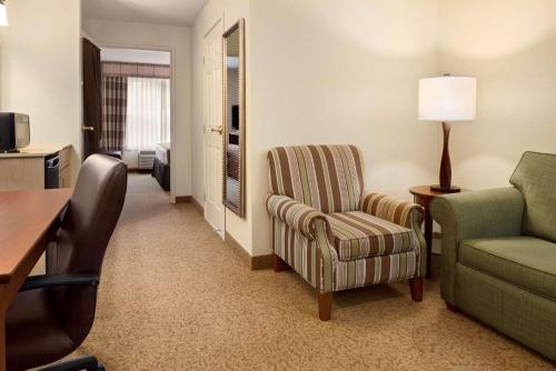 Country Inn & Suites by Radisson, Stevens Point, WI في ستيفنز بوينت: غرفة معيشة مع أريكة وكرسي