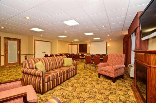 a conference room with couches and chairs and a flat screen tv at Country Inn & Suites by Radisson, Stevens Point, WI in Stevens Point
