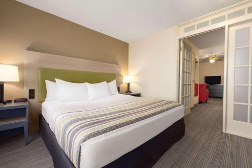 Country Inn & Suites by Radisson, Milwaukee Airport, WI في ميلووكي: غرفة فندق بسرير كبير ومخدات بيضاء