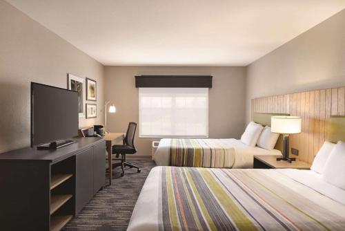 Country Inn & Suites by Radisson, Madison, WI في ماديسون: غرفة فندقية بسريرين وتلفزيون بشاشة مسطحة