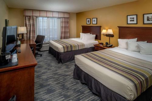 a hotel room with two beds and a flat screen tv at Country Inn & Suites By Radisson, Charleston South, WV in Charleston