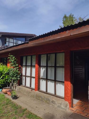 ein rotes Gebäude mit Fenstern und einer Tür in der Unterkunft Cabañas Lamani in Lago Puelo