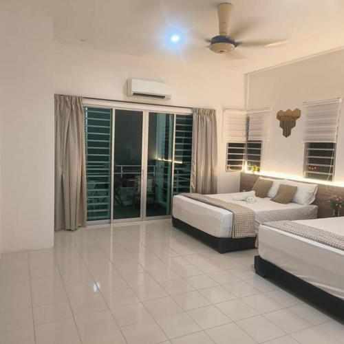 a bedroom with two beds and a ceiling fan at Taiping Holiday Home in Taiping
