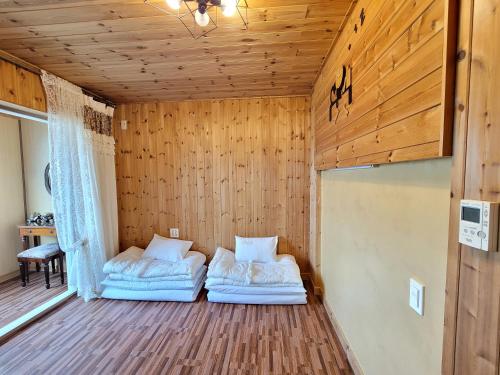 two beds in a room with wood paneling at Starlight drops Pension in Jeju