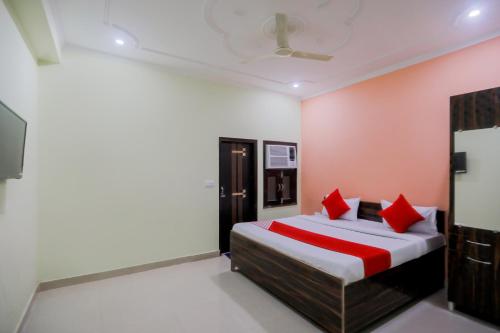 ein Schlafzimmer mit einem Bett mit roten Kissen in der Unterkunft OYO Karan Guest House in Faridabad