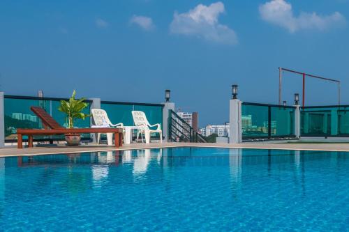 a swimming pool with two chairs and a table on a building at IRIS PALACE in Pattaya South