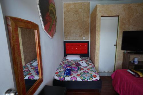 a small bedroom with a bed and a mirror at Hotel Arte Santa Rosa in Santa Rosa de Cabal