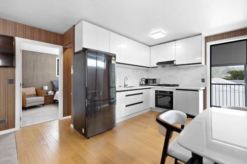 a kitchen with white cabinets and a stainless steel refrigerator at The Headley Loft in Queenstown