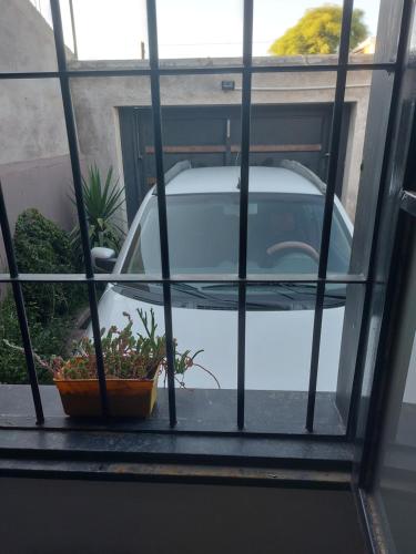 une voiture garée devant une fenêtre avec une plante en pot dans l'établissement Complejo PG HENTAI, à Jesús María
