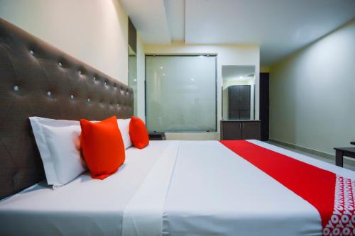 a bedroom with a large bed with orange and white pillows at OYO Kings Inn in Ludhiana