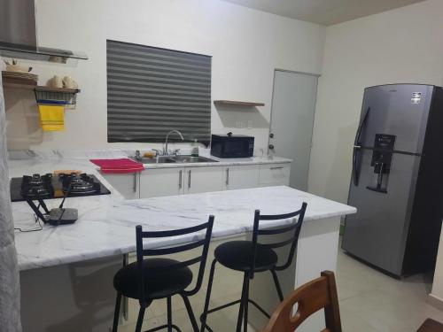 a kitchen with a counter and three bar stools at Salamanca Residencial in Hermosillo