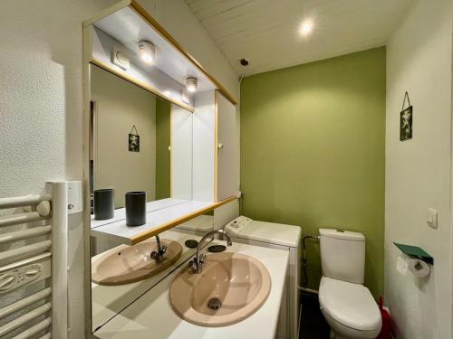 une salle de bain avec un lavabo, des toilettes et un miroir dans l'établissement Charmant T2 au cœur du Mont-Dore, idéal pour 4 pers, face aux thermes, animaux acceptés - FR-1-608-259, à Le Mont-Dore
