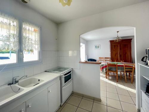 une cuisine blanche avec un évier et une table dans l'établissement Maison conviviale près de la plage avec jardin clos, 2 chambres, animaux admis - FR-1-231-299, à Bretignolles-sur-Mer