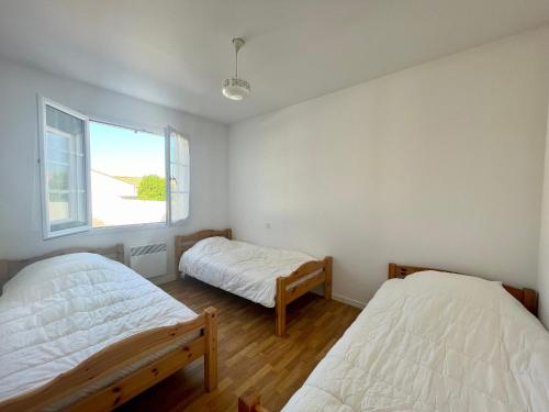 une chambre avec deux lits et une fenêtre dans l'établissement Maison conviviale près de la plage avec jardin clos, 2 chambres, animaux admis - FR-1-231-299, à Bretignolles-sur-Mer