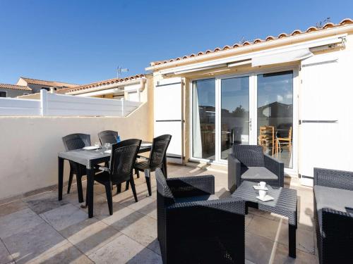 un patio avec une table et des chaises sur un balcon dans l'établissement Charmant Pavillon Climatisé avec Mezzanine, Piscine et Parking - Près de la Plage! - FR-1-409-247, à Fleury