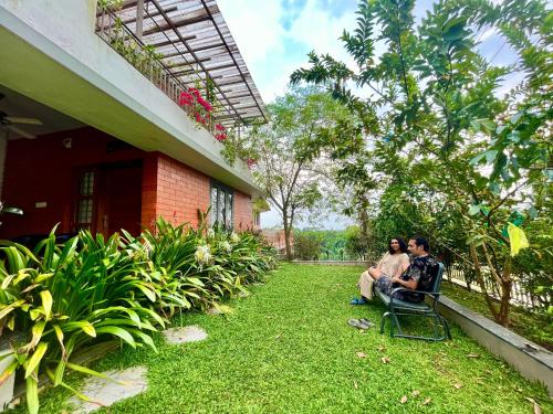 two people sitting on a chair outside of a house at Green Horizon, Luxury & Nature at Kothamangalam in Kotamangalam