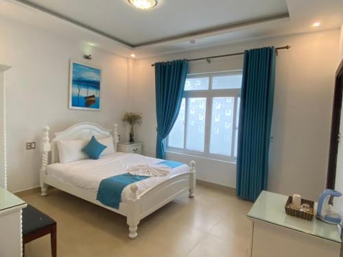 Schlafzimmer mit einem Bett mit blauen Vorhängen und einem Fenster in der Unterkunft THIÊN SANG HOTEL in Xuan An