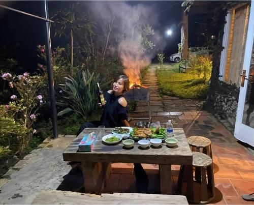 a little girl sitting at a table with a fire at Family house - stay on pine hill Dalat in Xuan An