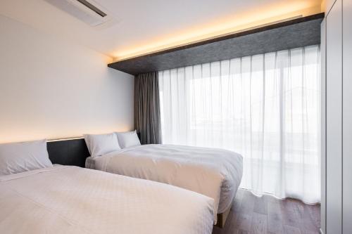 two beds in a hotel room with a window at Hotel Dios - Vacation STAY 31239v in Awaji