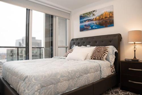 a bedroom with a large bed and a large window at Cozy 1.5 Bedroom near Square One in Mississauga
