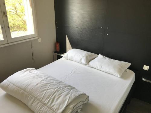 un lit avec des draps blancs et des oreillers dans une chambre dans l'établissement À 5 min de la plage, terrasse cosy, appart moderne proche du centre et port - Cap d'Agde - FR-1-723-119, au Cap d'Agde