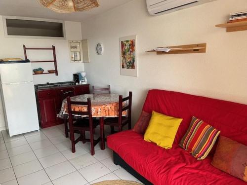 un salon avec un canapé rouge et une cuisine dans l'établissement Appartement T2 cabine - Proche plage, commerces et piscine sécurisée - FR-1-749-35, au Cap d'Agde