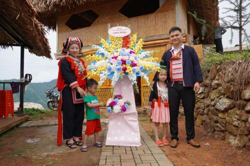 a man and two children standing next to a flower arrangement at Hoàng Su Phì - Móng Ngựa Homestay in Ha Giang