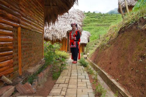 a woman walking down a path next to a building at Hoàng Su Phì - Móng Ngựa Homestay in Ha Giang