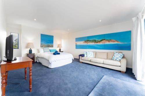 a bedroom with a bed and a couch and a tv at Stoneferry- A Beachfront Beauty - Free Wifi in Port Elliot