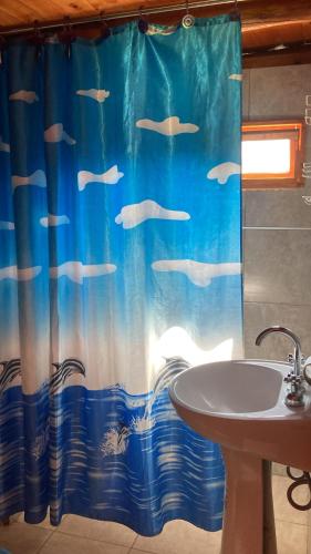 a bathroom with a sink and a shower curtain with fish at Cabañas doña vivi in Valle Hermoso