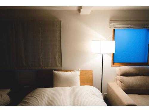 um quarto com uma cama, um candeeiro e uma janela em ＳＯ Ｋｙｏｔｏ Ｆｕｓｈｉｍｉ Ｉｎａｒｉ - Vacation STAY 76147v em Quioto