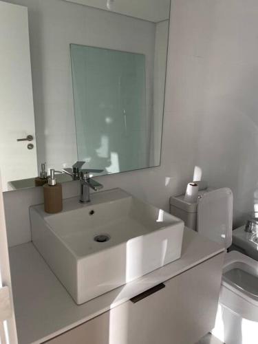 a white bathroom with a sink and a mirror at Apto a estrenar en Punta in Punta del Este