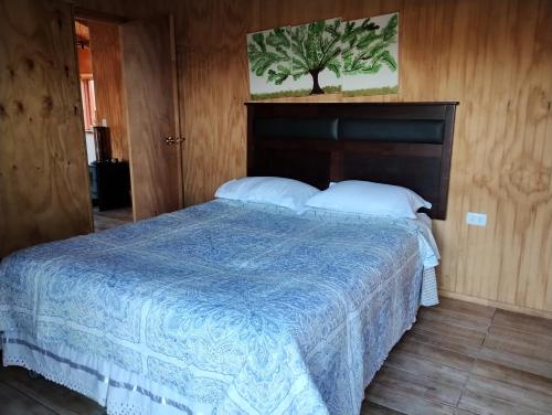 1 dormitorio con 1 cama con edredón azul en CABAÑAS BRISAS VOLCANICAS, en Cunco