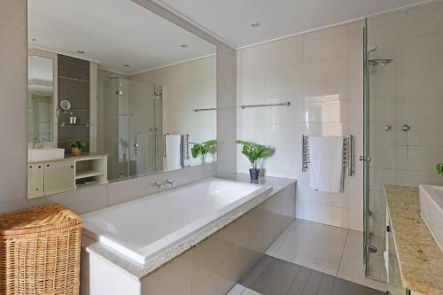 a bathroom with a large tub and a glass shower at Unit 305 Cape Royale Luxury Apartments in Cape Town