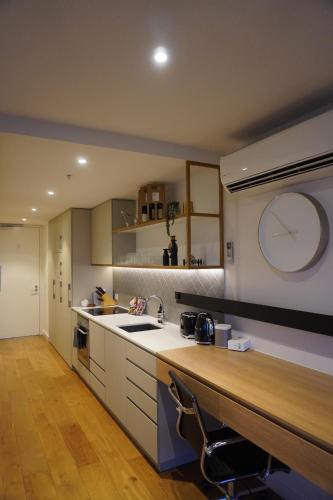 a kitchen with a sink and a clock on the wall at Metro Retreat on Burnley in Melbourne