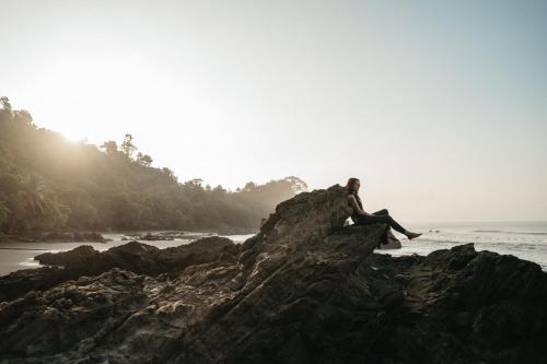 a person sitting on a rock on the beach at ACHIOTÉ Architectural Gem - Adults Only in Uvita