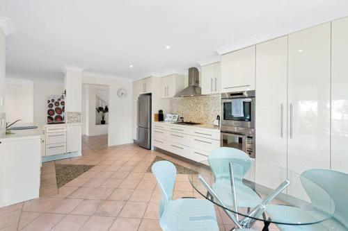 a kitchen with white cabinets and a glass table and chairs at Spacious & Serene! 3Bed/2Bath/2+Cars ~ House in Mount Ommaney