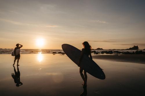 a man and a woman standing on the beach with a surfboard at ACHIOTÉ Architectural Gem - Adults Only in Uvita