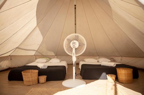 a white fan in a tent with two beds at Porã Chacahua in Guayabas