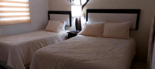a bedroom with two beds with white sheets and a window at Serenity Home Hospedaje con confort y seguridad in Mérida