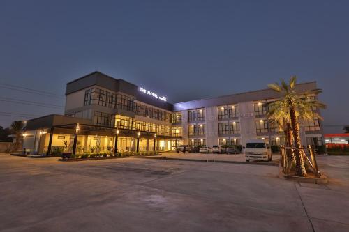 um grande edifício com uma palmeira em frente em โรงแรม เดอะโมเดล การ์เด้น em Yasothon
